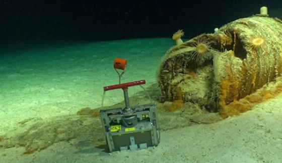 Un des fûts de déchets radioactifs présentant une dégradation importante et un déversement de matière sur les fonds marins environnants. On voit, à côté, le dispositif d’échantillonnage des sédiments déployé puis récupéré par le Nautile à 4 700 mètres de profondeur, en 2026. Crédits: Campagne NODSSUM, CNRS, Flotte océanographique française, Ifremer, Miso Facility/WHOI, Fourni par l'auteur